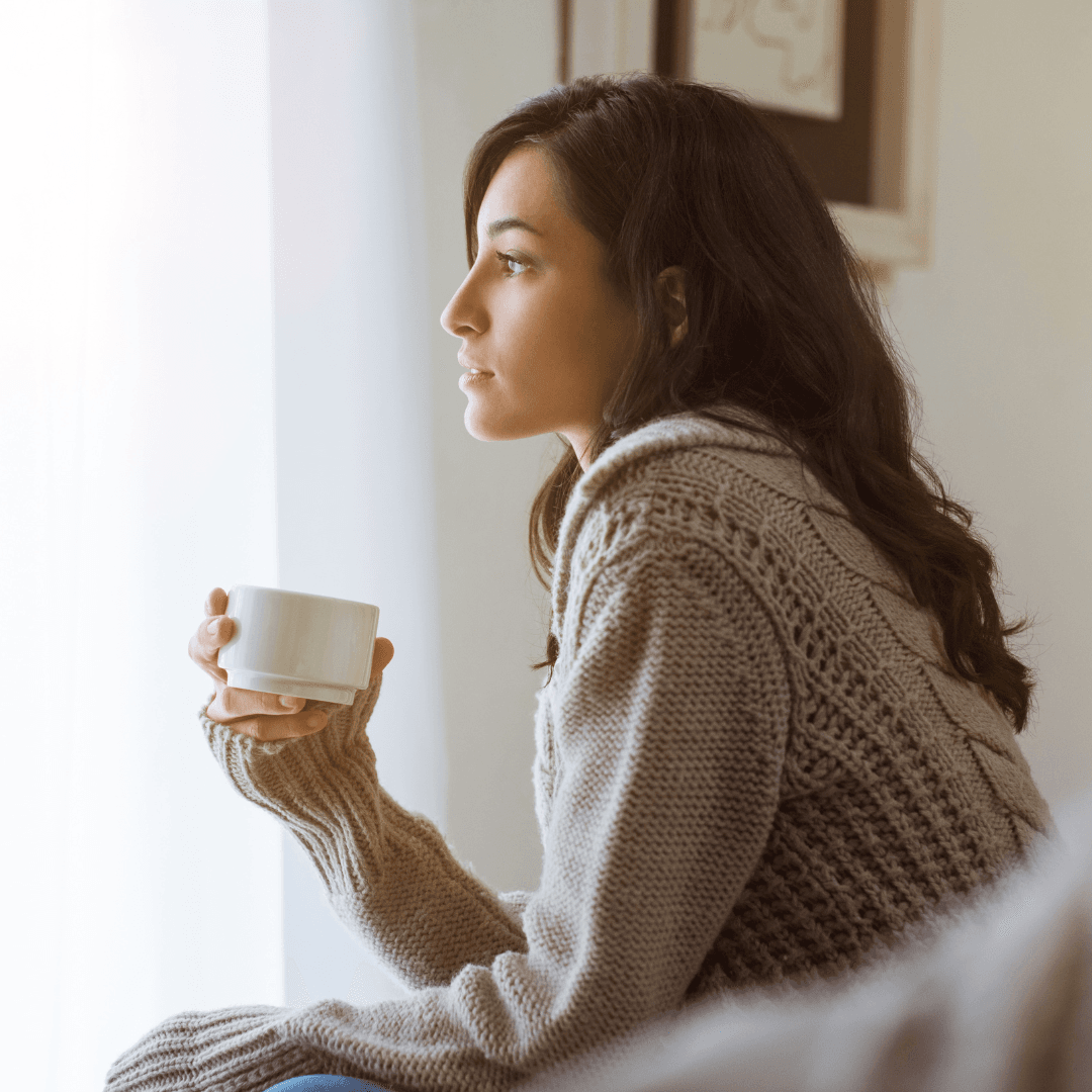 Picture of a woman holding her morning coffee, gazing out the window at the sunrise and "preflecting" about her upcoming day.