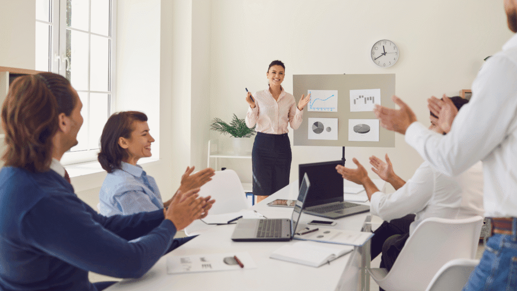 Picture of an SMB leader at the front of a meeting room with an engaged audience, who is applauding her and the quality of her meeting.