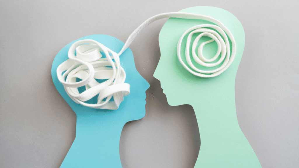 Image of two paper head cutouts with a winding string running in each head and between them, a stylized representation of empathy.