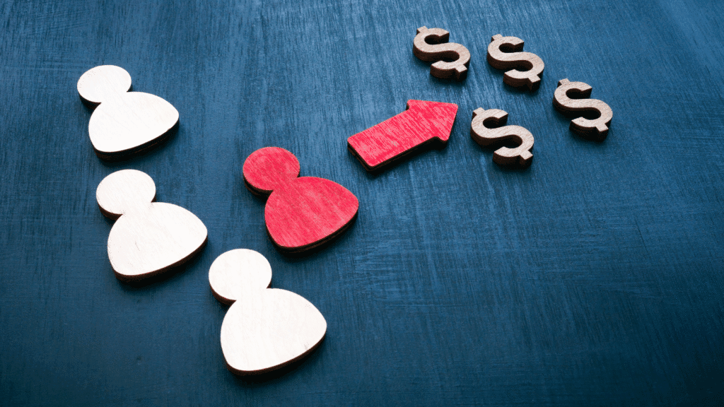 Picture of wooden cutouts of people on the left, one of which is coloured red, with a wood cutout of a red arrow pointing from the people to a series of wooden cutout dollar signs. Meant to represent the focus on customer value and ROI to drive success in your SMB.