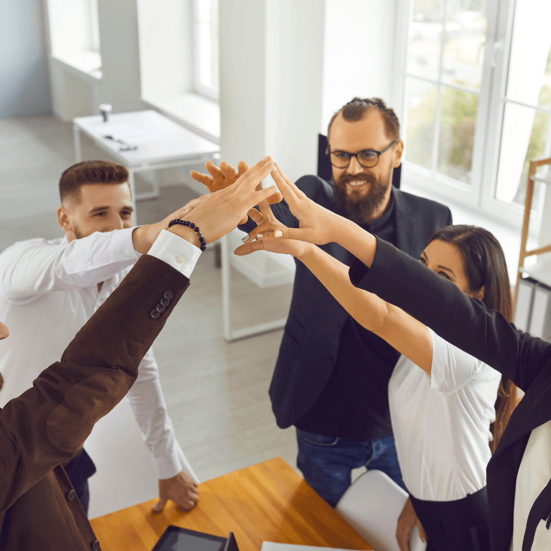 An SMB business team raise their hands together as a team in a "go team "motion, celebrating the importance of leadership being a team sport.