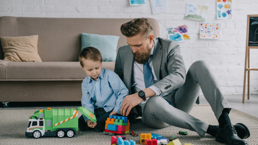 Image of an SMB leader dressed in a suit playing with his young son on the floor of the office.