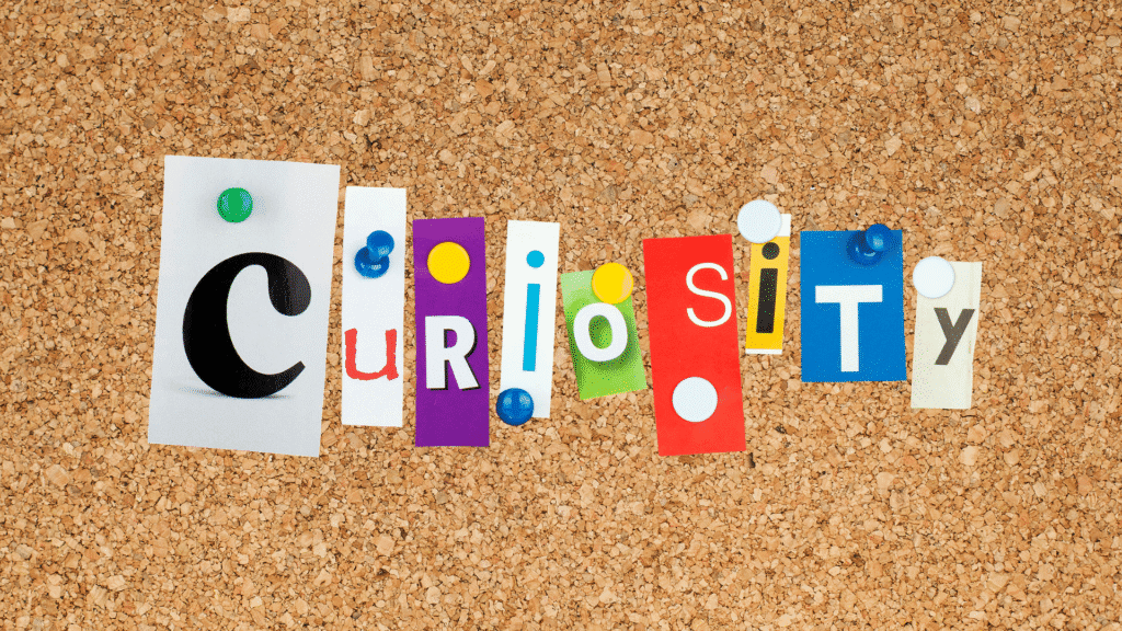 Picture of a cork board with letters cut from magazines pinned to it spelling out the word "curiosity"