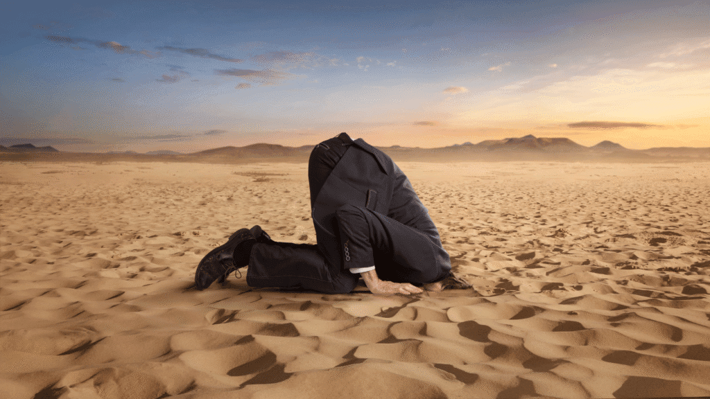Image of an SMB leader with his head in the sand, an illustration of "Ostrich Syndrome" where business politics makes people keep their head down rather than sharing important truths that need to be heard.